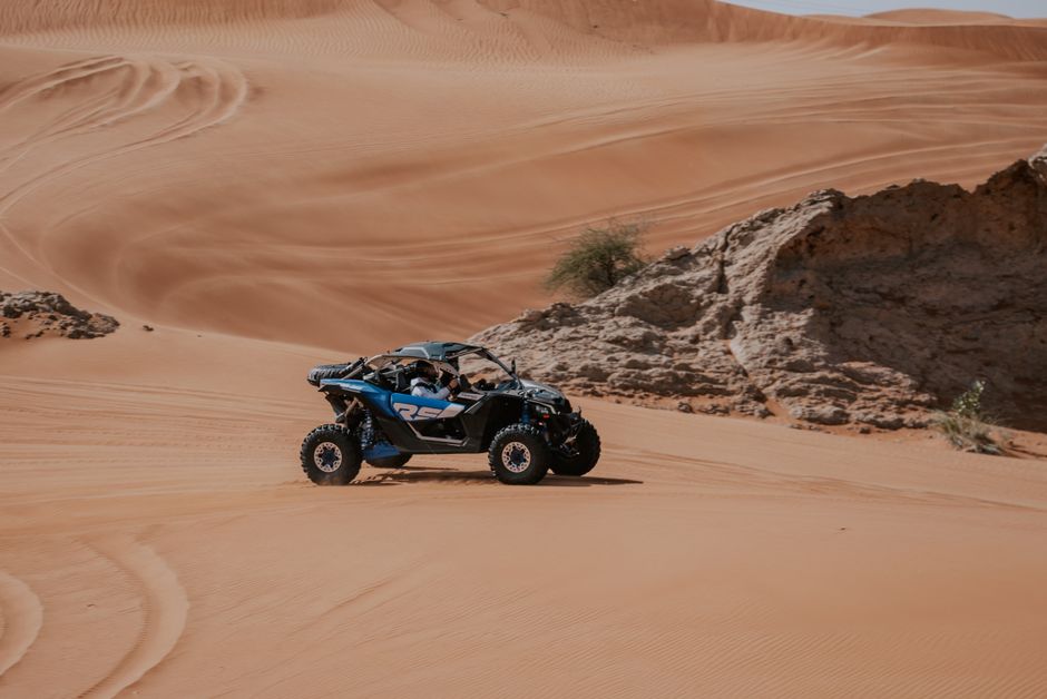 A blue Can-Am Maverick navigating through the expansive desert terrain.