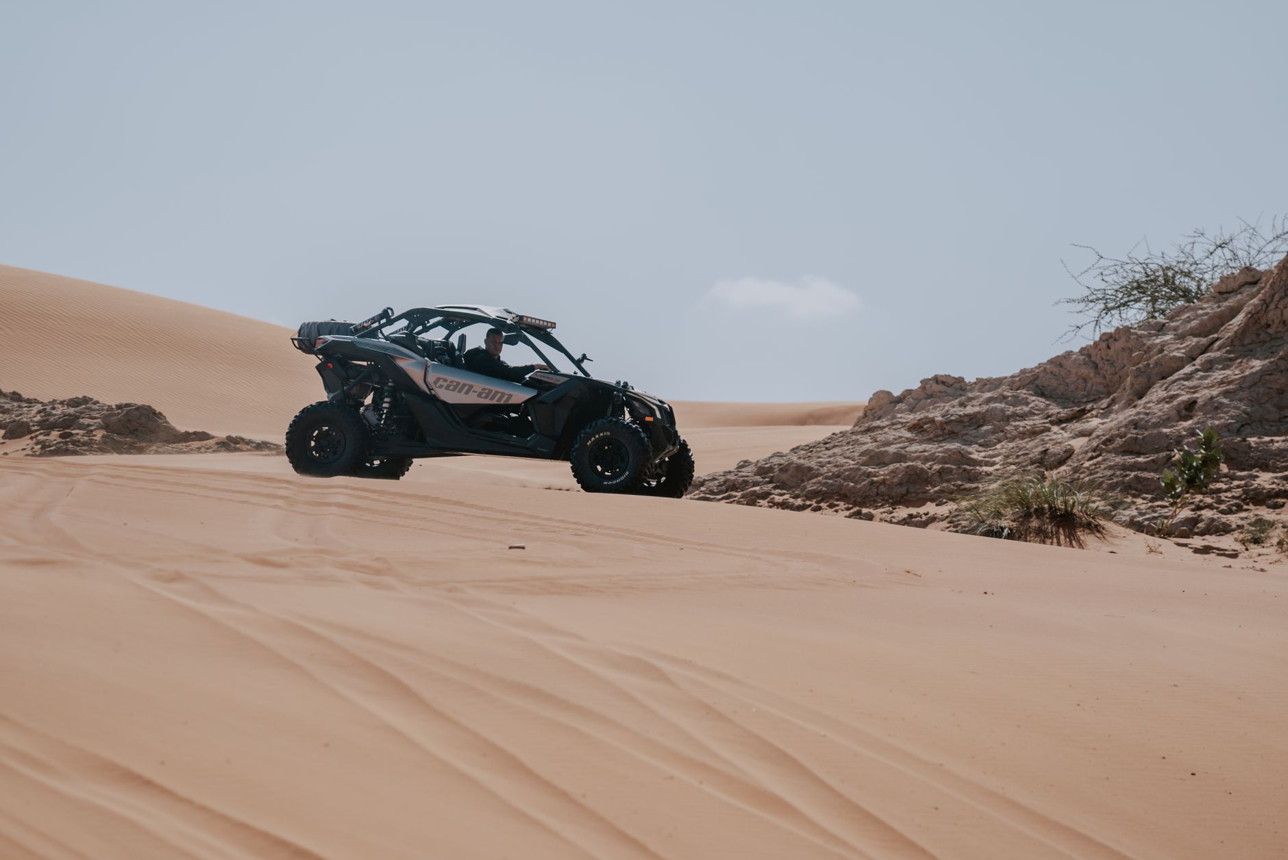 Can-Am side-by-side UTV riding across desert sand dunes on an off-road trail