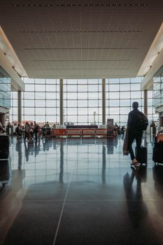 Busy airport terminal with travelers, luggage, and modern architecture.