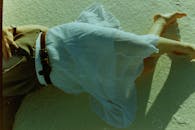 一名女子赤脚躺在沙滩上，穿着白色裙子，捕捉到复古风格