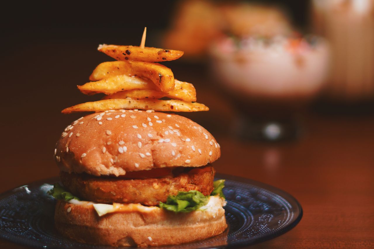 tempting burger topped with crispy french fries on a plate showcasing