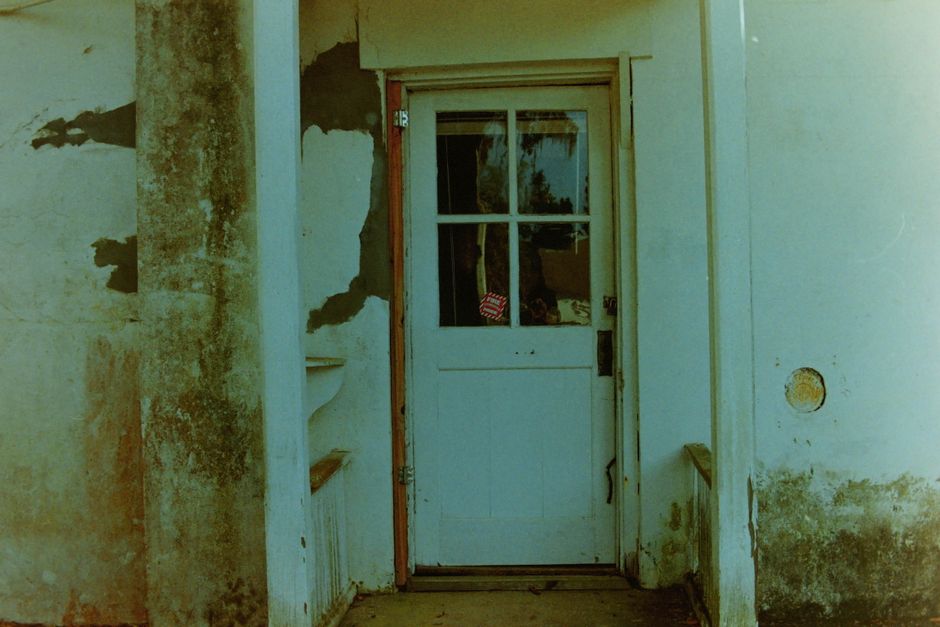 Broken door frame and scattered debris at the entrance of a residential apartment after a confrontation