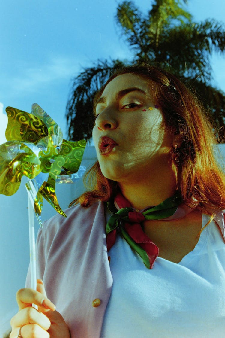 Woman Blowing On A Paper Windmill On A Stick