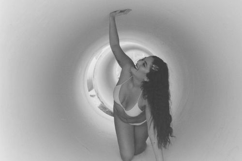 Free Smiling woman in bikini kneeling in a grayscale tunnel with long hair. Stock Photo