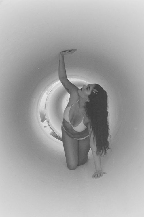 Free Grayscale image of a woman in a bikini crawling elegantly inside a tunnel. Stock Photo
