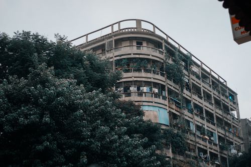 Free A multi-story residential building with balconies surrounded by lush trees in a downtown area. Stock Photo