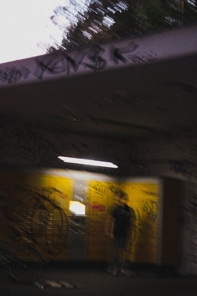 Blurred Photo Of Person Standing Under Lit Up Postal Box