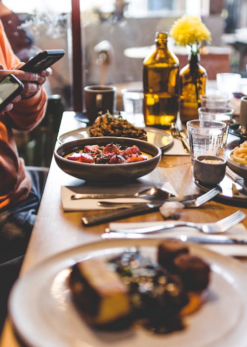 Free A Person Taking a Picture of Food on a Dining Table Stock Photo