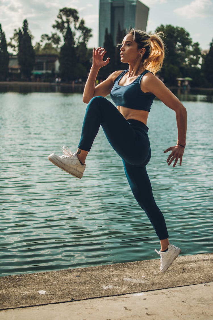 Woman Midair Exercising Near Water 