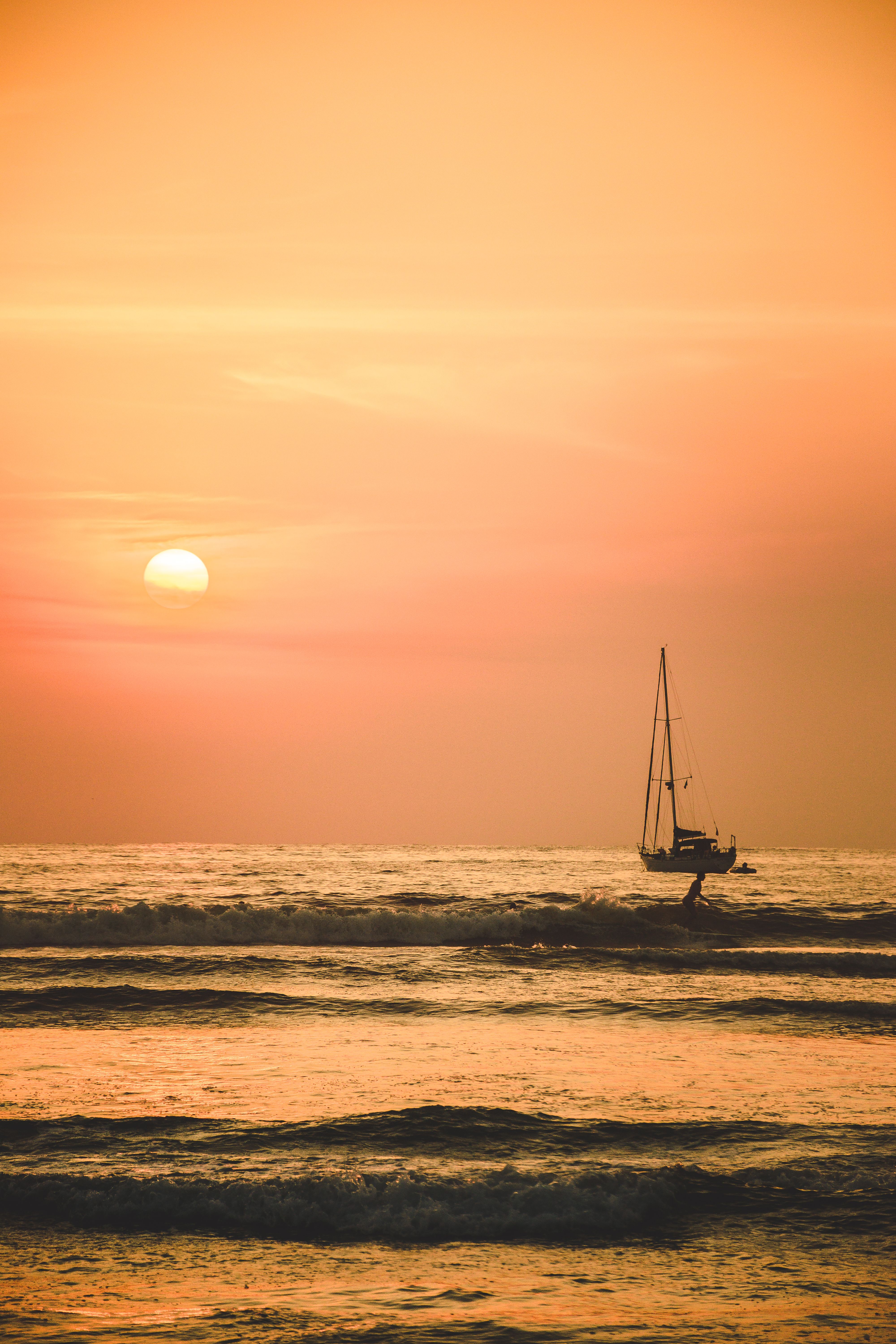 A stunning sailboat silhouette captured at sunset in Gro., Mexico, with vibrant orange hues reflecting on calm ocean waves.