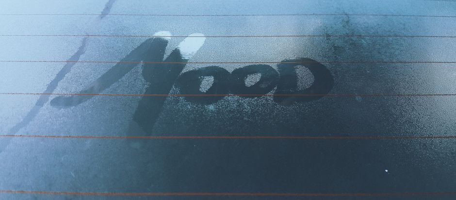 Moist car window with 'mood' written in fog, evoking a contemplative atmosphere.