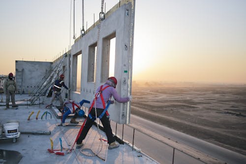 Group of anonymous builders installing reinforced concrete construction at sunset
