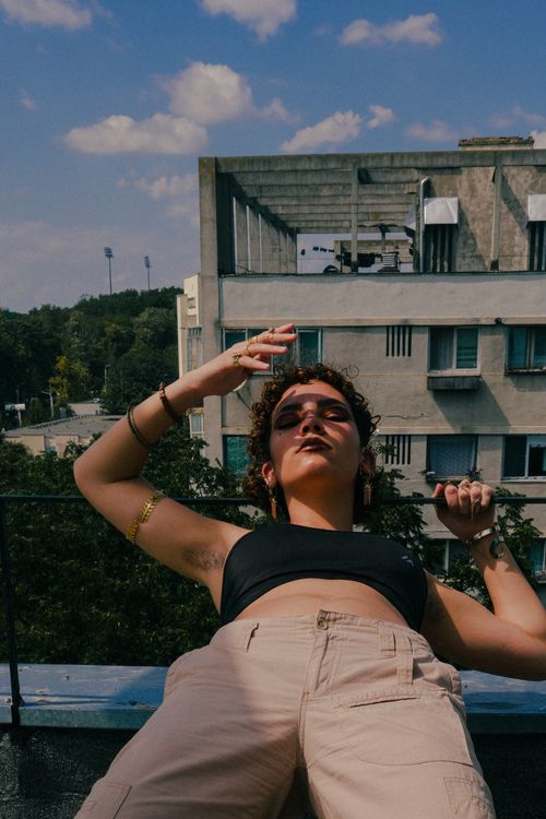 Free Fashionable woman in casual attire posing confidently on a rooftop under a clear sky. Stock Photo