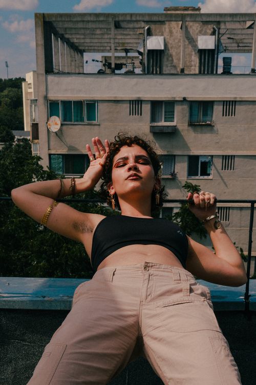 Free Model confidently posing on a city rooftop against a backdrop of urban architecture. Stock Photo