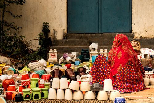 Free Colorful handmade pottery on display at a street market, with a woman in traditional attire. Stock Photo