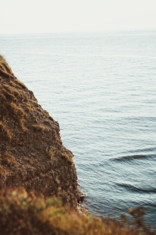 Free A breathtaking view of a cliff with a calm ocean surface, ideal for travel and nature enthusiasts. Stock Photo