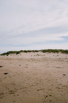 Tranquil beach with dunes and clouds, perfect for relaxation and coastal exploration.