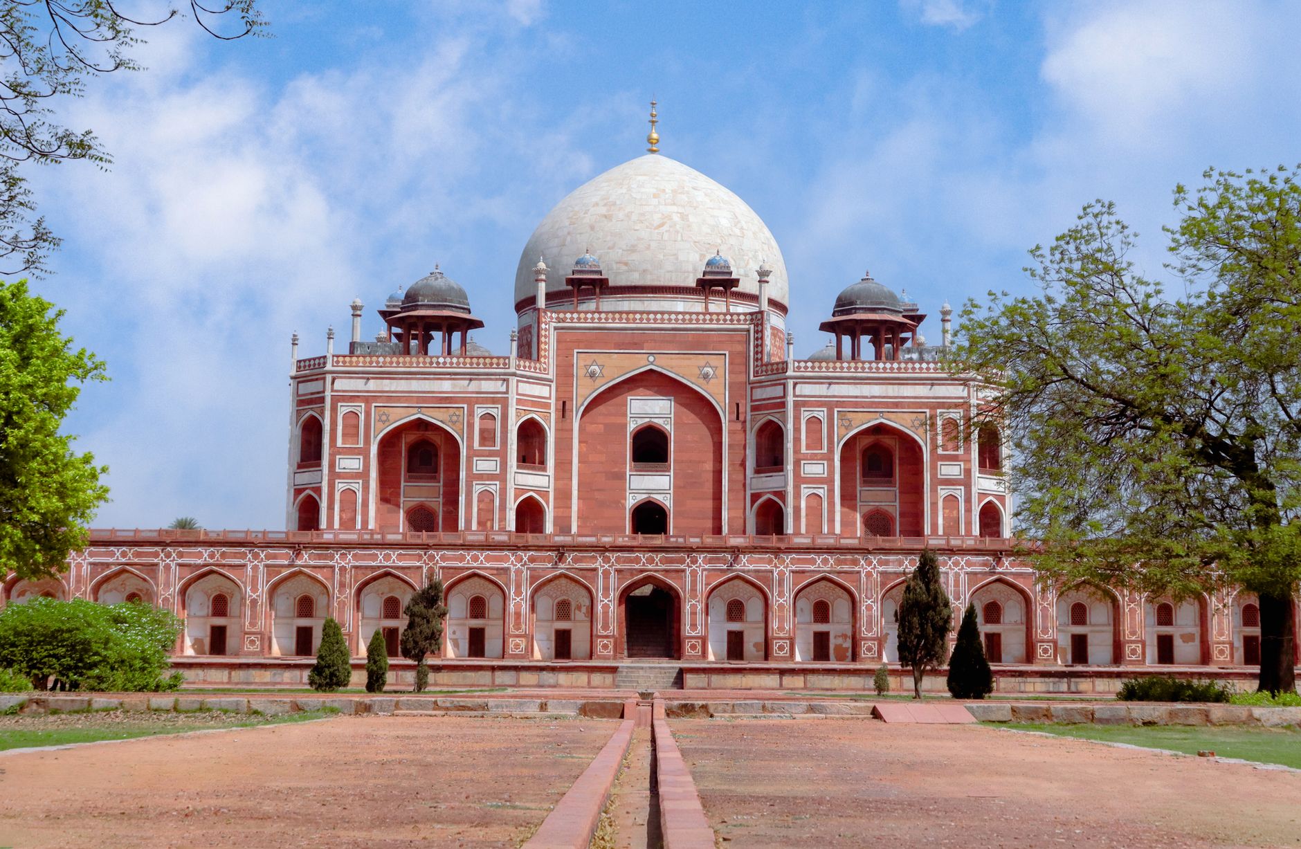 Sandstone gateway of Humayun's Tomb with visitors crossing the lawn