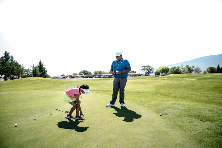 Man Standing Beside Girl Picking Ball