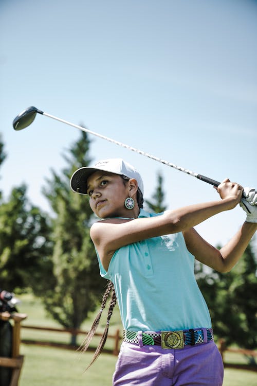 Gadis Bermain Golf Dekat Pepohonan Hijau