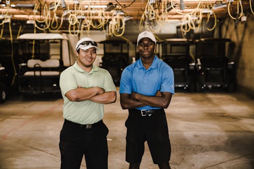 Free Two Men Crossing Arms While Standing Near Golf Carts Stock Photo