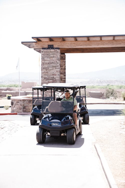 Man Wearing Grey Polo Shirt Riding Blue and White Golf Cart