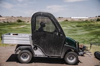 一辆多功能车停在室外的高尔夫球场上，天空晴朗