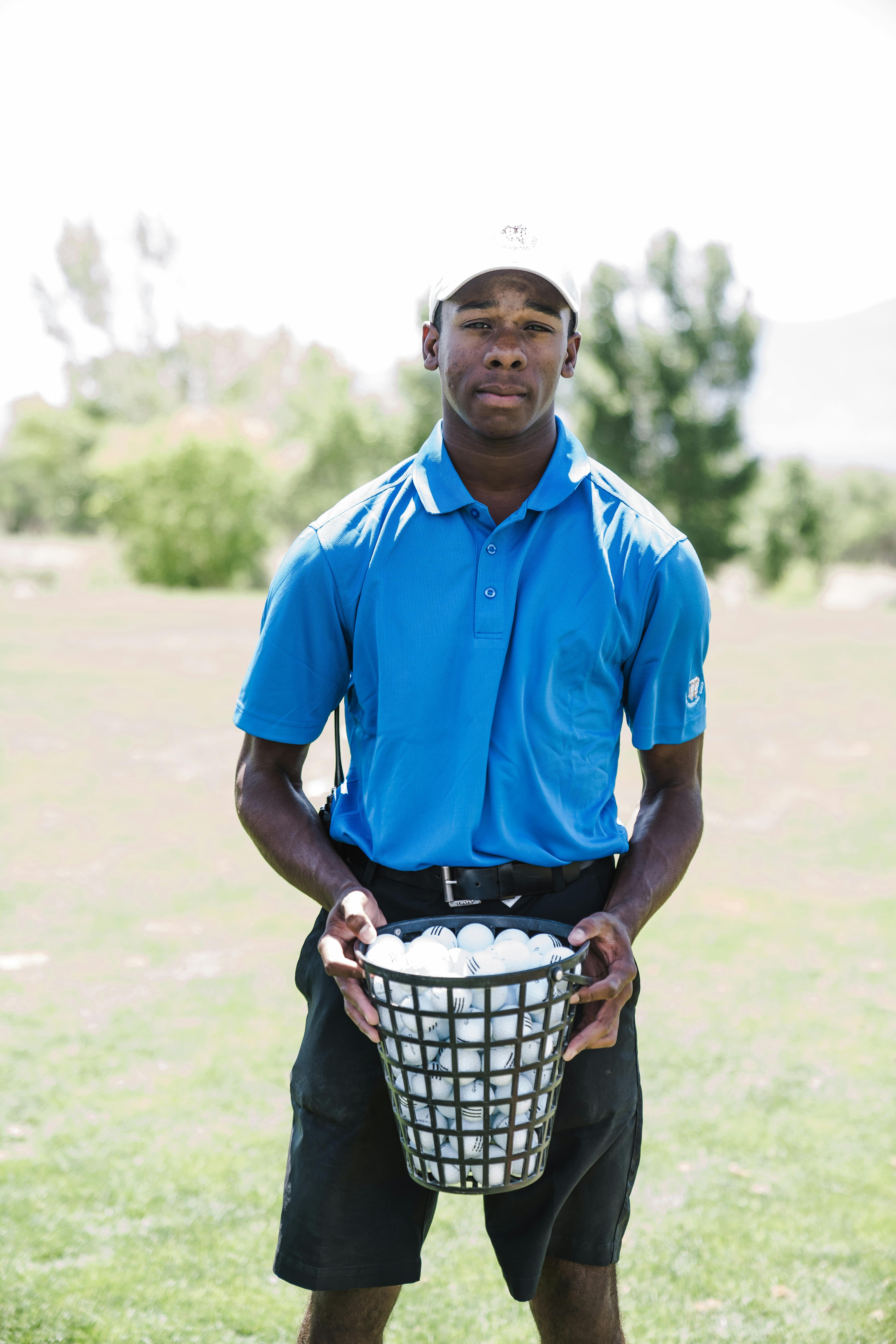 man holding basket of golf balls