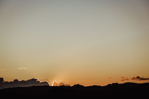 Free Captivating sunset with golden hues highlighting mountain silhouettes under a clear sky. Stock Photo