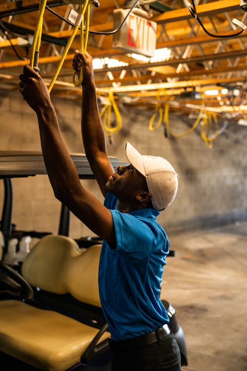 Man in White Cap and Blue Shirt Reaching A Yellow Rope