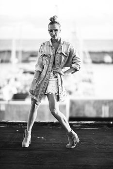 Black and white photo of a fashionable woman in denim posing confidently.
