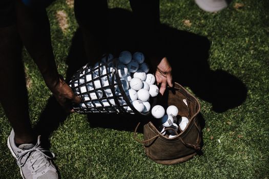 Person Pouring Golf Balls in Brown Leather Bag