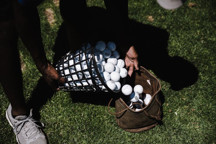 Person Pouring Golf Balls In Brown Leather Bag