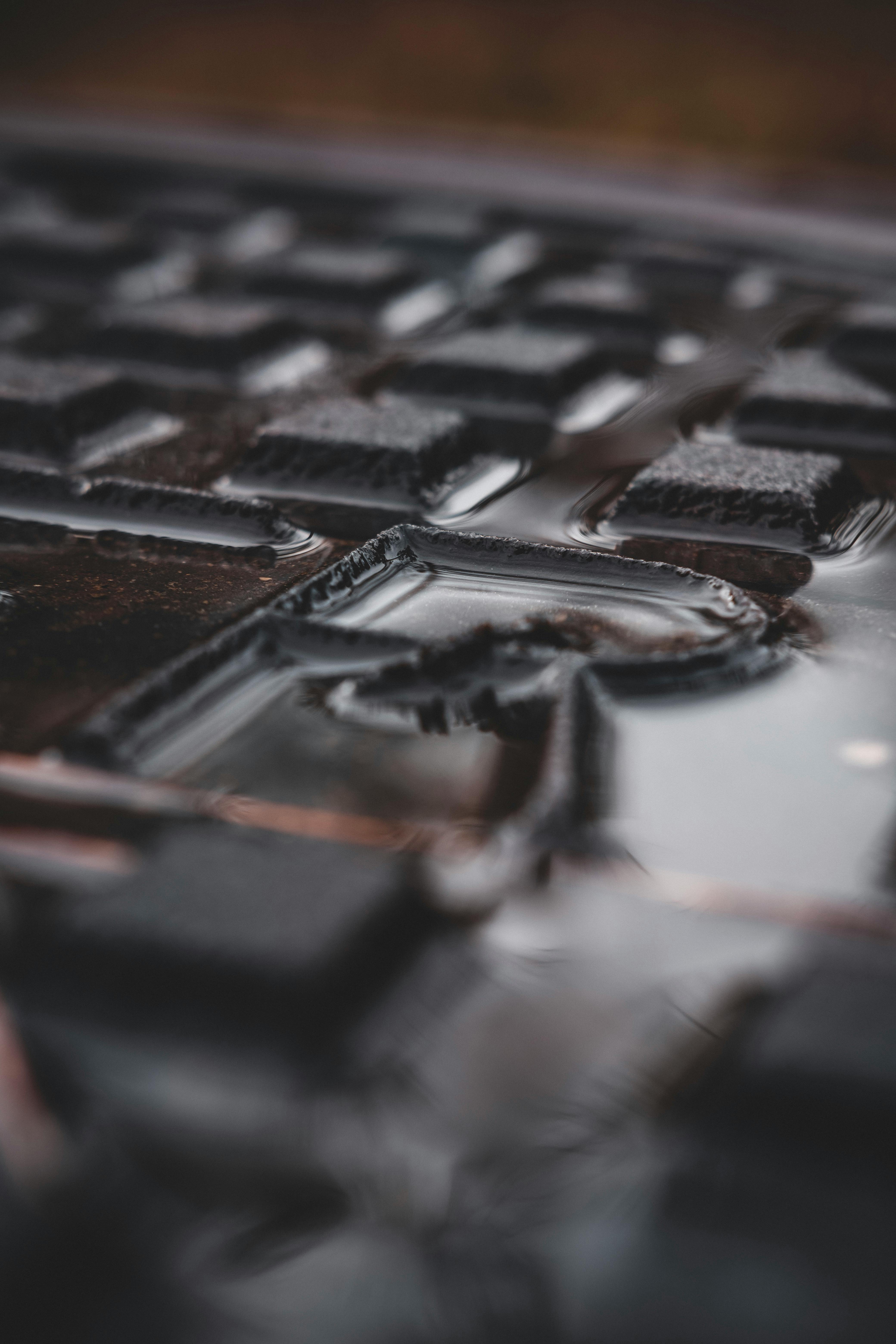 Detailed shot of a wet metal surface with geometric patterns and water droplets.