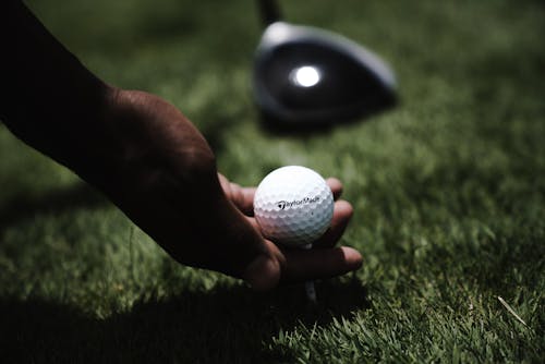 Persona Sosteniendo Una Pelota De Golf Blanca En El Suelo