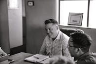 一个男人在舒适的办公室里开会，面带微笑，画面被处理成单色