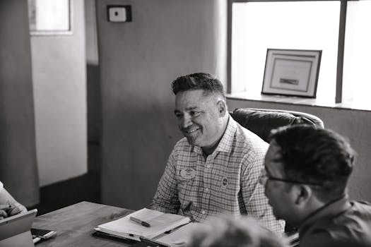 一个男人在舒适的办公室里开会，面带微笑，画面被处理成单色