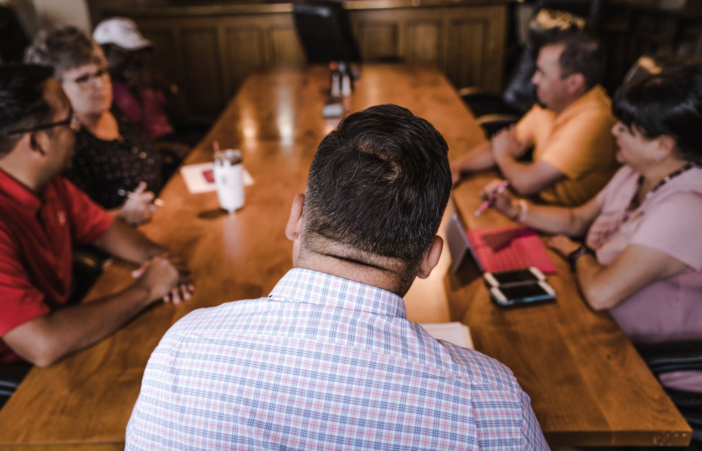 A business meeting with a diverse team discussing around a wooden table in an office setting.