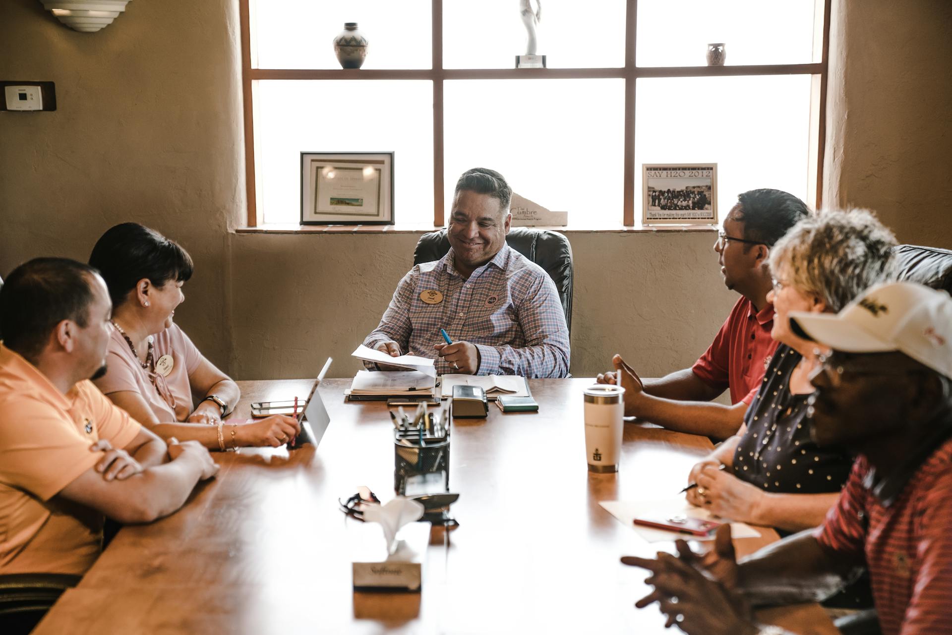 A diverse group of adults in a collaborative team meeting inside a well-lit office room.