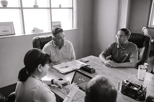 Grayscale Photo of People Inside A Room Having A Meeting