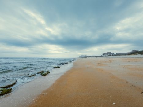 A serene beach with gentle waves and overcast skies, perfect for a peaceful getaway.
