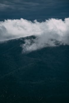 Dramatic view of mist-covered mountains under cloudy skies.