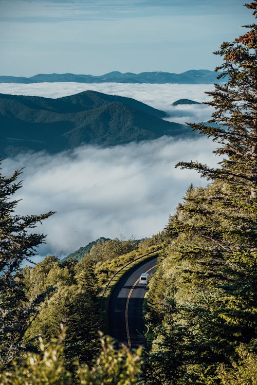 Car on Road and Mountains in Clouds