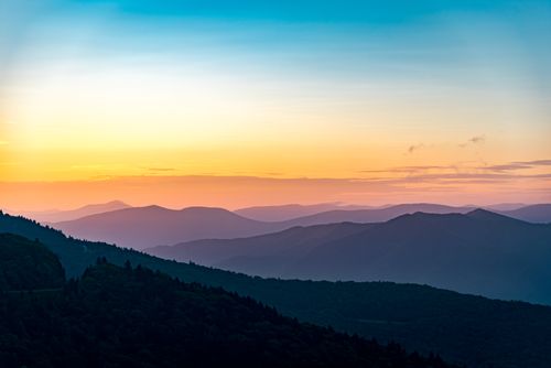 Free A breathtaking view of a peaceful mountain range illuminated by the soft hues of a sunrise. Stock Photo