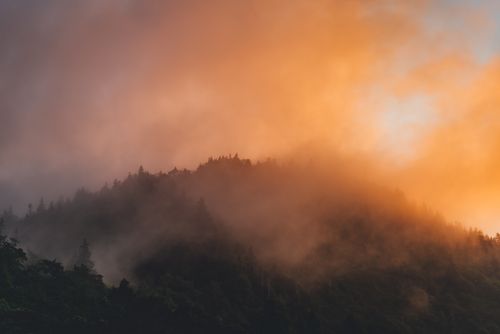 Free Breathtaking view of fog and mist enveloping a mountain during sunset, creating a mystical scene. Stock Photo