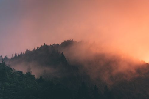 Free A serene mountain landscape enveloped in mist and sunset hues. Stock Photo