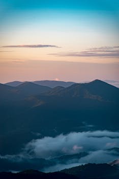 A breathtaking aerial view of mountain peaks blanketed in clouds at sunrise, creating a picturesque landscape.