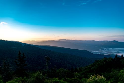 Free Explore a stunning mountainous vista with a blue sky and lush greenery at dawn. Stock Photo