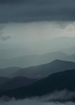 A dramatic mountain landscape shrouded in mist and dark clouds, creating a mysterious atmosphere.