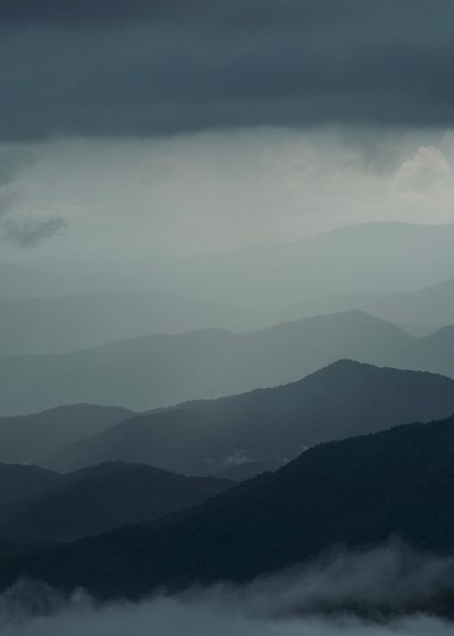 Free A dramatic mountain landscape shrouded in mist and dark clouds, creating a mysterious atmosphere. Stock Photo